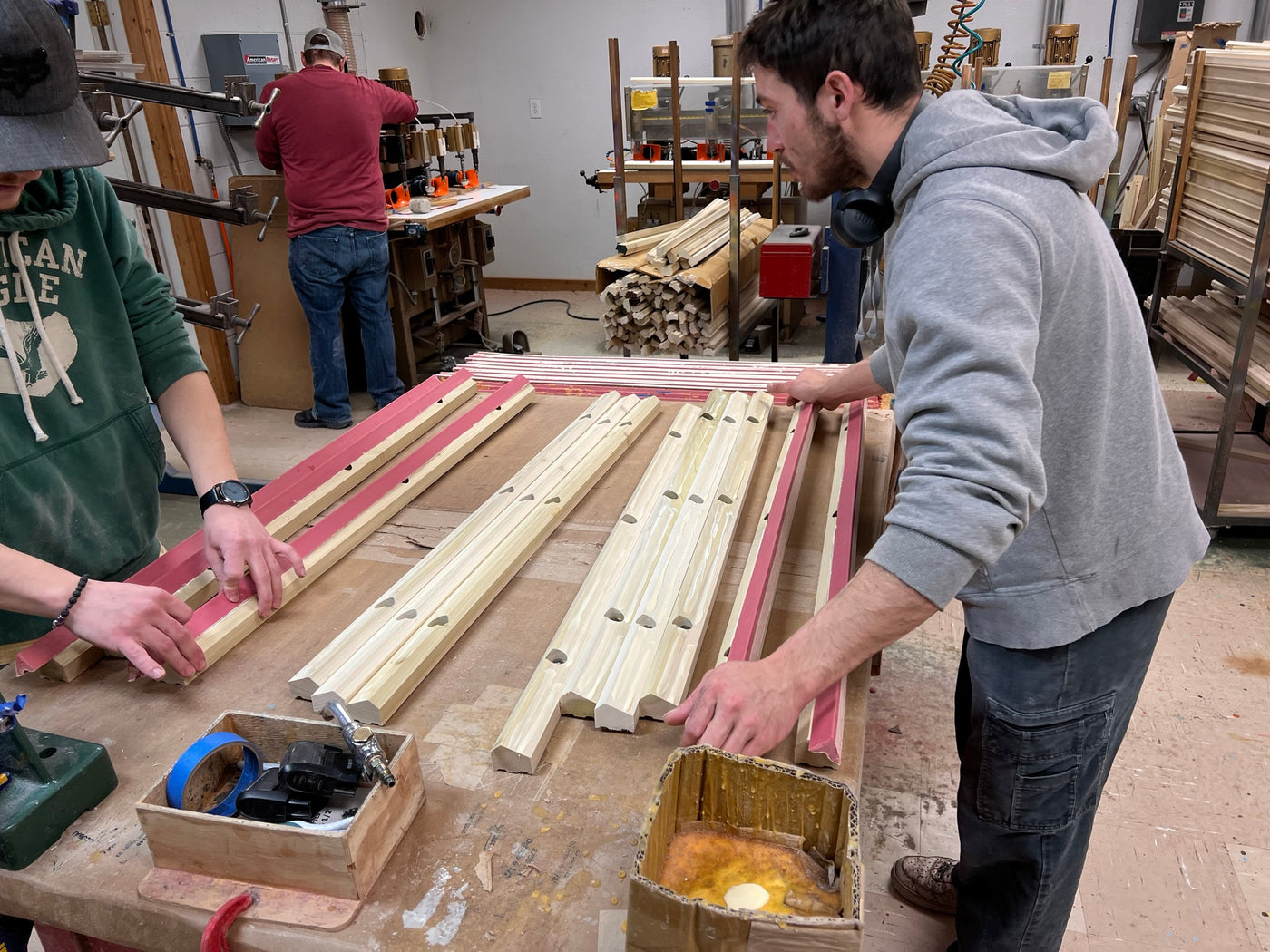 Two team members align and glue rubber to the solid wood rail blanks